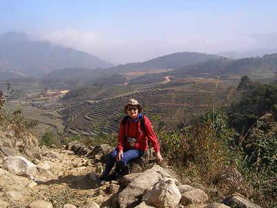 Mary hiking near Sapa in Vietnam. Hilly countryside, with stepped farming terraces in the background.