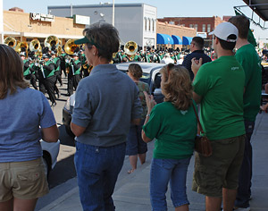 Group of people watches the University of North Texas marching band in the parade
