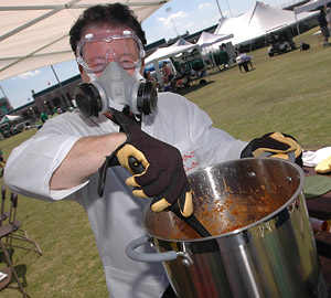 Man stirring chili while wearing a gas mask and goggles