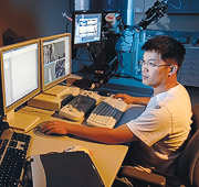 Student at computer workstation with four monitors