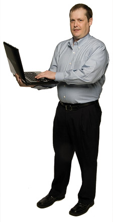 Daniel L. Spears standing with an open laptop computer. (Photo by Mike Woodruff)