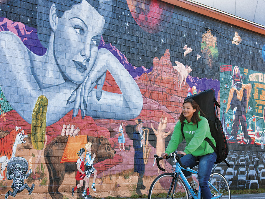 UNT student biking in front of Denton art