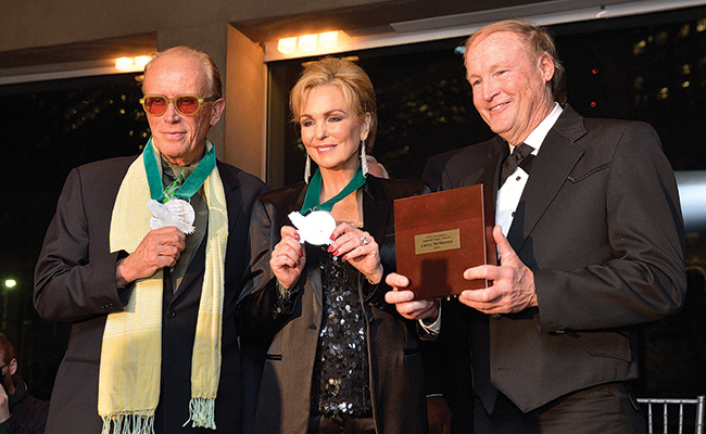 2014 alumni honorees Peter Weller ('70) and Phyllis George with George Getschow, principal lecturer in the Frank W. and Sue Mayborn School of Journalism, accepting for Larry McMurtry ('58). (Photo by Michael Clements)