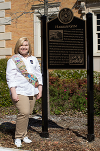 Elise Clements beside the Harriss Gym campus historical sign