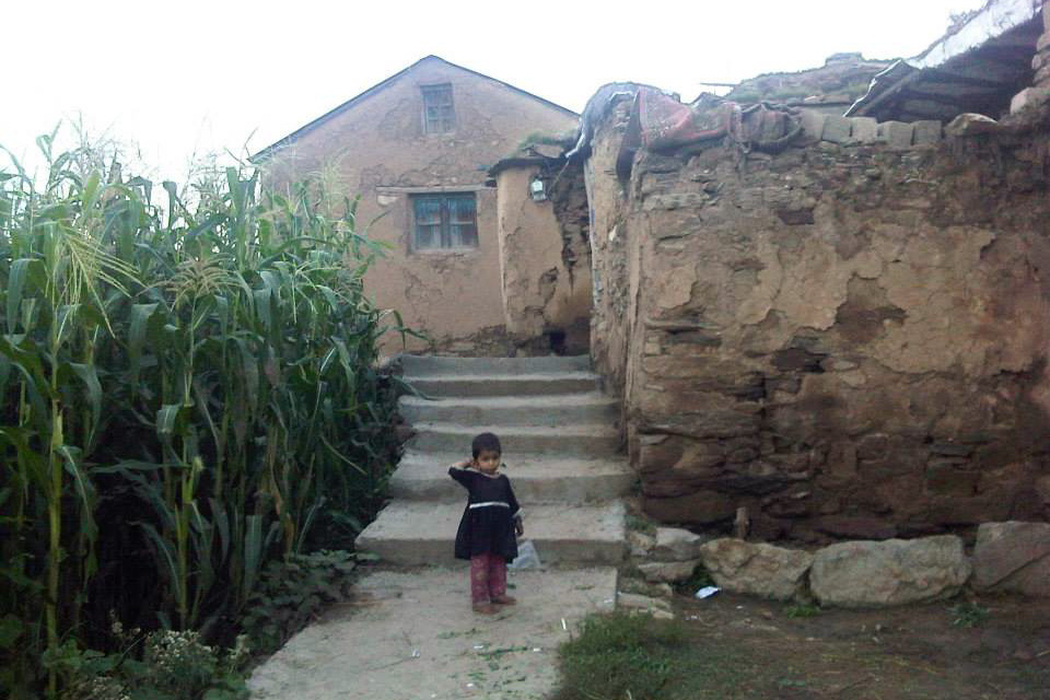 Child standing in front of a stone building