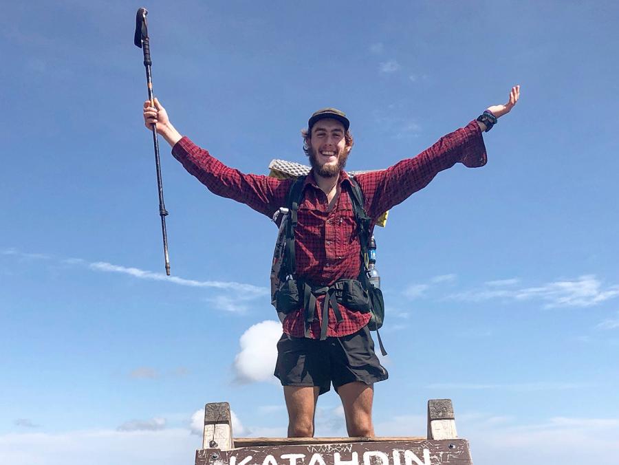 Brett Luce stands on top a sign for the Katahdin Baxter peak