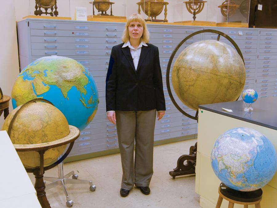 Paulette Marie Hasier standing with numerous globes and file cabinets