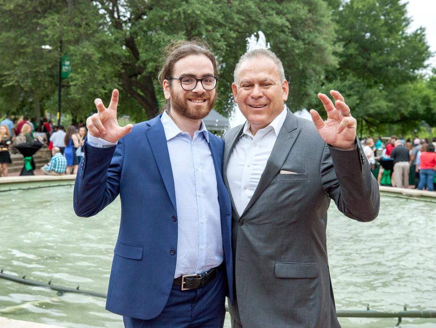John Solis with his father, Javier making the UNT eagle claw in front of the library mall fountain