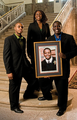 The Uduebor family in the Hurley Administration Building, (left to right) Valentine Uduebor ('08), Cynthia Uduebor ('00) and Lovett Uduebor with a photo of their brother, Otis ('06). (Photo by Jonathan Reynolds)