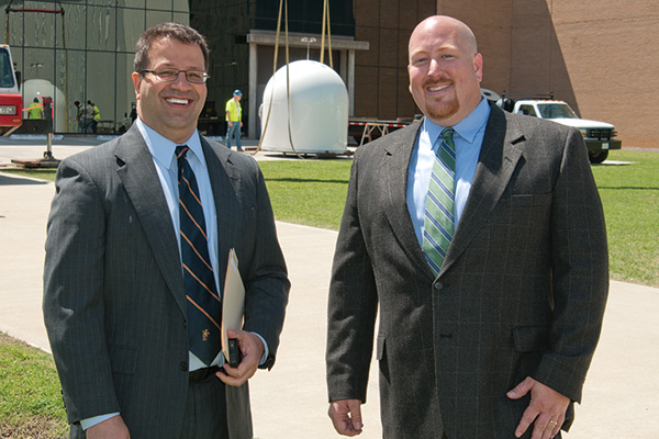 From left, Andrew Harris, vice president for finance and administration, and Randy Fite, director of facilities maintenance, at the Collaborative Adaptive Sensing of the Atmosphere radar installation at UNT's Discovery Park, this spring. (Photo by Jonathan Reynolds)
