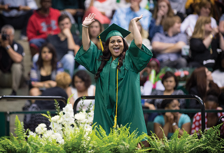 UNT student on stage at commencement wear cap and gown regalia
