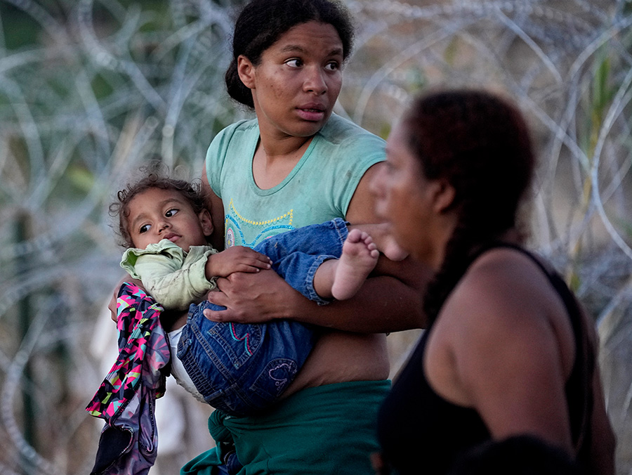 A woman carries her child after she and other migrants