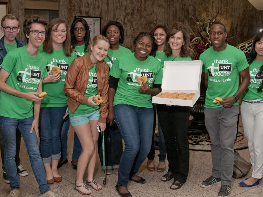 Students standing with box of doughnuts 