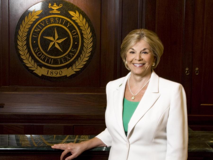 Gretchen Bataille standing in front of UNT seal