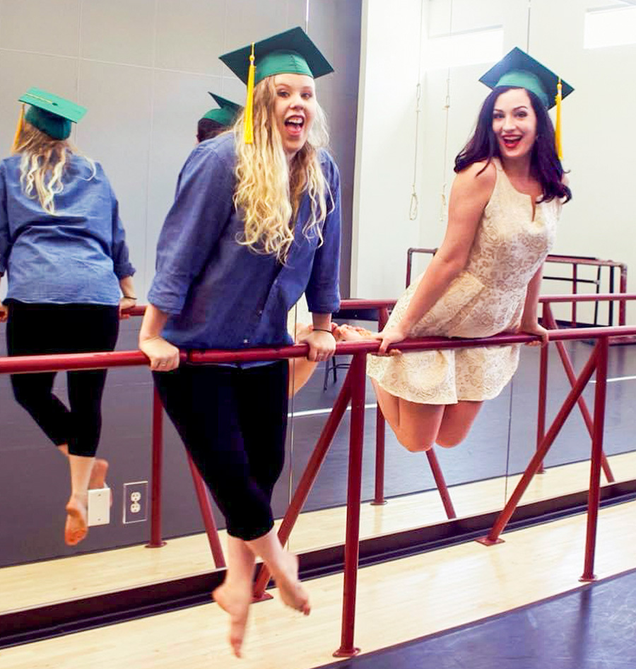 Ginny Wheeler and Danielle Willis wearing their mortar board caps in a a dance studio